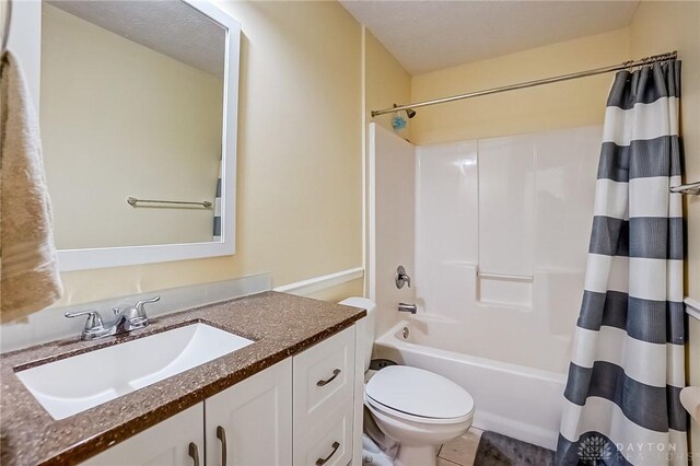 full bathroom with shower / tub combo with curtain, tile patterned flooring, vanity, toilet, and a textured ceiling