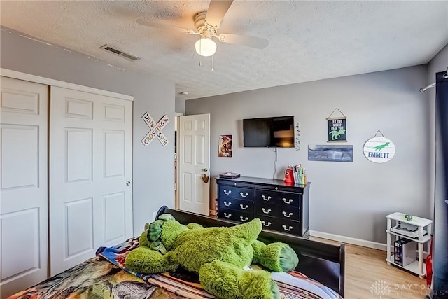 bedroom with a closet, ceiling fan, a textured ceiling, and light hardwood / wood-style flooring