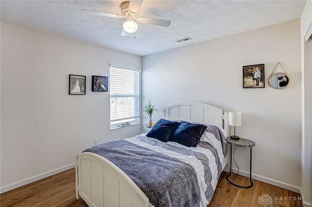 bedroom featuring hardwood / wood-style floors, a textured ceiling, and ceiling fan