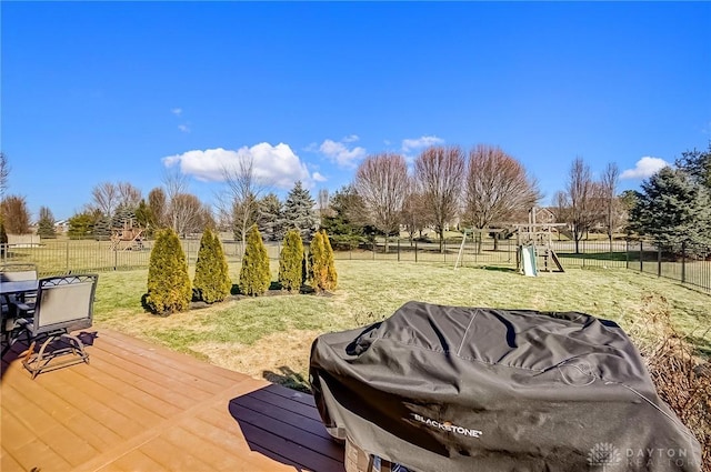 deck with a rural view, a lawn, and a playground