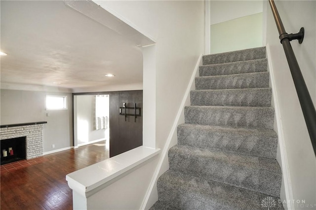 staircase with a brick fireplace and hardwood / wood-style floors