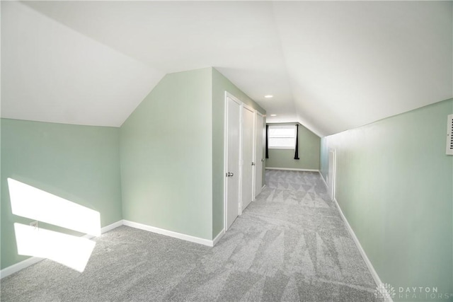 corridor with vaulted ceiling and light carpet