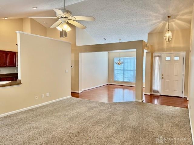 carpeted foyer entrance featuring ceiling fan, high vaulted ceiling, and a textured ceiling