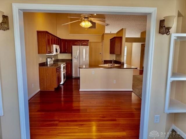 kitchen with dark hardwood / wood-style flooring, sink, white appliances, and ceiling fan