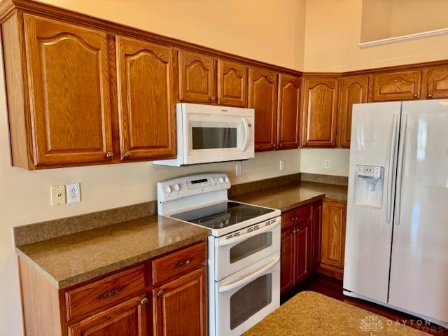 kitchen with white appliances and dark stone countertops