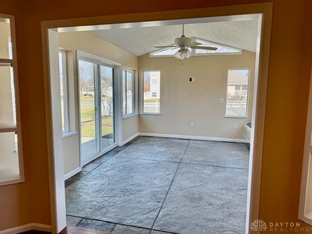 empty room with ceiling fan, vaulted ceiling, and a healthy amount of sunlight