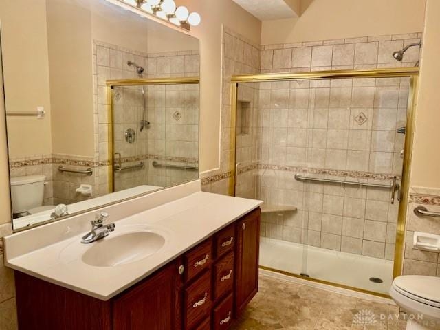 bathroom with a shower with door, vanity, and toilet