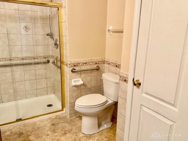 bathroom featuring toilet, tile patterned flooring, a shower with door, and tile walls