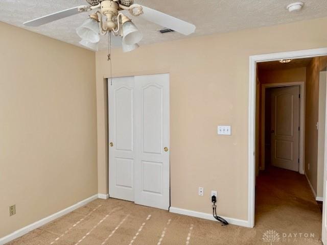 unfurnished bedroom with ceiling fan, light colored carpet, a textured ceiling, and a closet