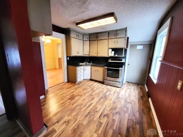 kitchen featuring sink, stainless steel electric range, a textured ceiling, light hardwood / wood-style floors, and backsplash