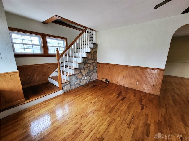 unfurnished living room with hardwood / wood-style flooring, ceiling fan, and wood walls