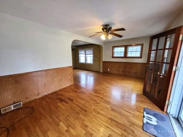 empty room featuring wooden walls, light hardwood / wood-style floors, and ceiling fan