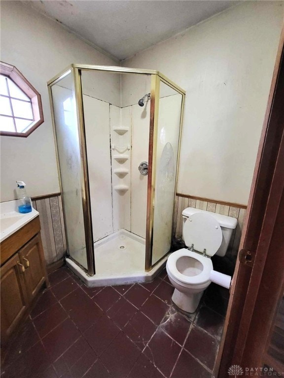 bathroom featuring an enclosed shower, vanity, tile patterned flooring, and toilet