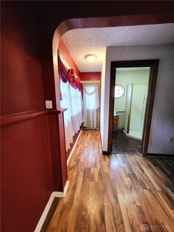 hallway with hardwood / wood-style floors and a textured ceiling