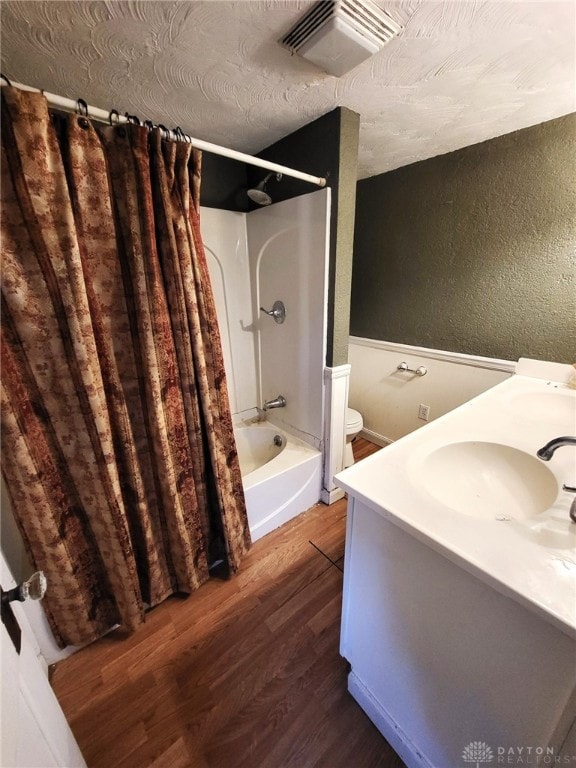 full bathroom with shower / tub combo with curtain, toilet, a textured ceiling, vanity, and hardwood / wood-style flooring