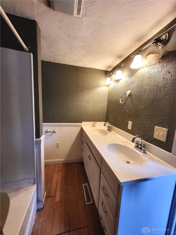 bathroom featuring hardwood / wood-style flooring, vanity, and a bath