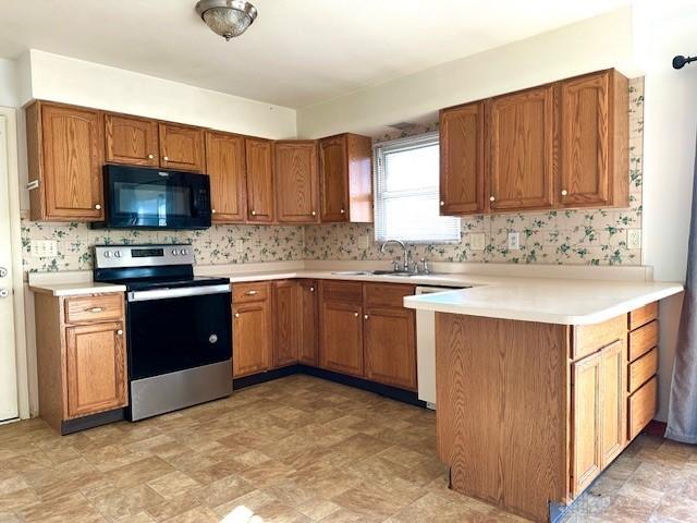 kitchen featuring brown cabinets, stainless steel electric stove, light countertops, a sink, and black microwave