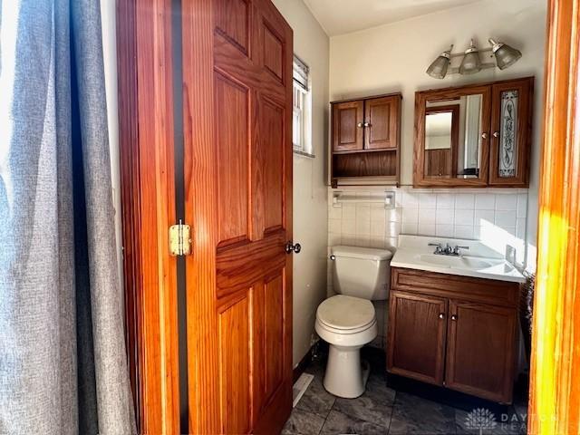 bathroom featuring tasteful backsplash, vanity, and toilet