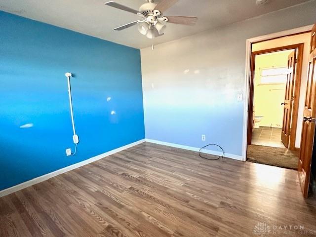 unfurnished room with ceiling fan, baseboards, and wood finished floors