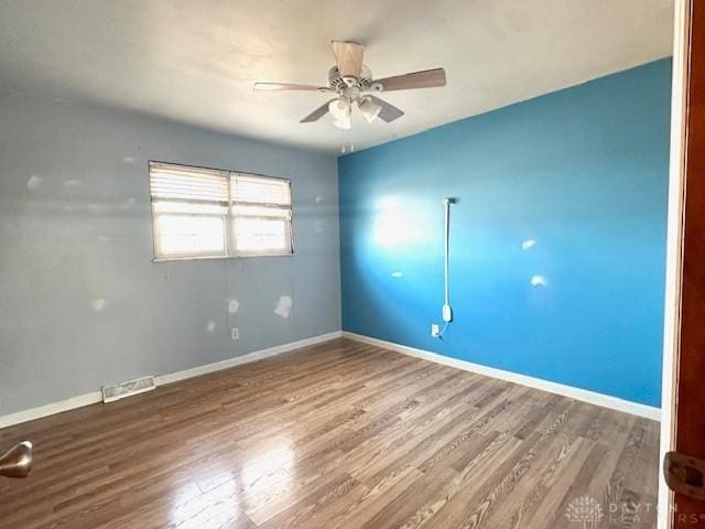 unfurnished room with visible vents, ceiling fan, baseboards, and wood finished floors