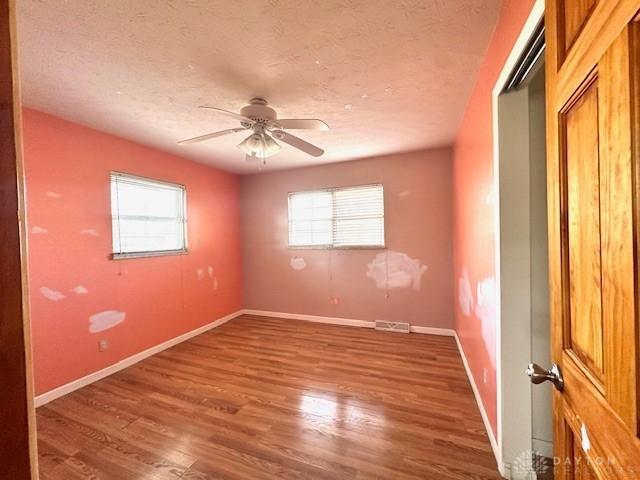 unfurnished bedroom featuring visible vents, baseboards, ceiling fan, wood finished floors, and a textured ceiling