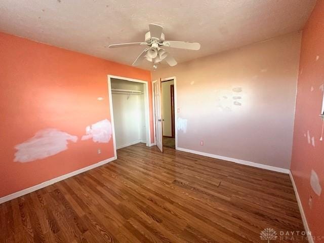 unfurnished bedroom featuring a ceiling fan, a closet, baseboards, and wood finished floors