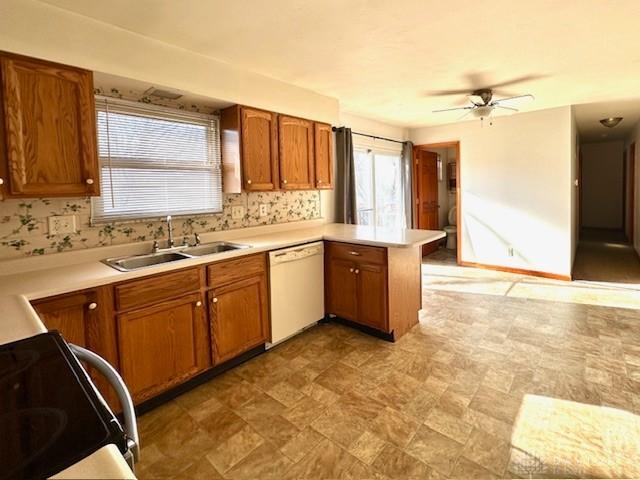 kitchen featuring range with electric cooktop, a peninsula, white dishwasher, light countertops, and a sink