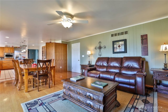 living room featuring light hardwood / wood-style flooring, ornamental molding, and ceiling fan