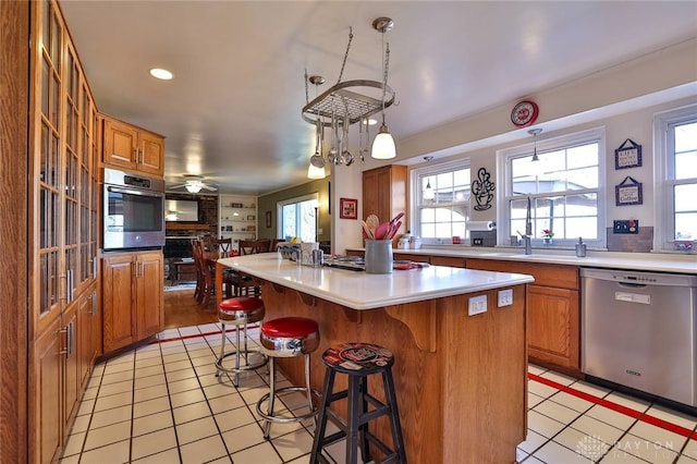 kitchen featuring stainless steel appliances, decorative light fixtures, a center island, and a breakfast bar area