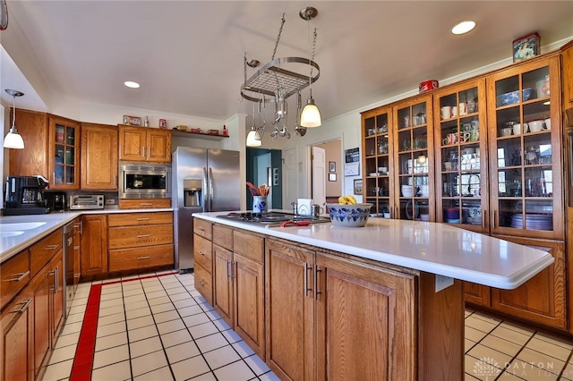 kitchen with sink, light tile patterned floors, appliances with stainless steel finishes, a center island, and decorative light fixtures