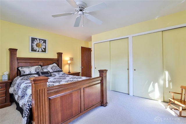 carpeted bedroom featuring multiple closets and ceiling fan