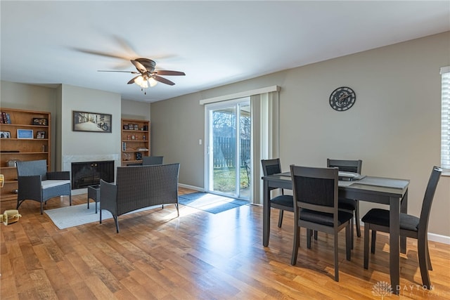 dining space with ceiling fan, a premium fireplace, and light hardwood / wood-style flooring