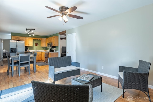 living room with ceiling fan, rail lighting, sink, and light hardwood / wood-style flooring