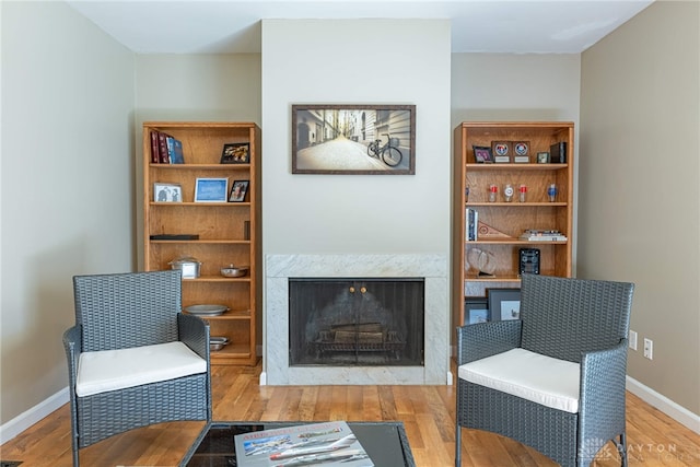 living area featuring wood-type flooring and a high end fireplace