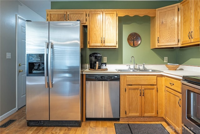 kitchen with sink, light wood-type flooring, and appliances with stainless steel finishes