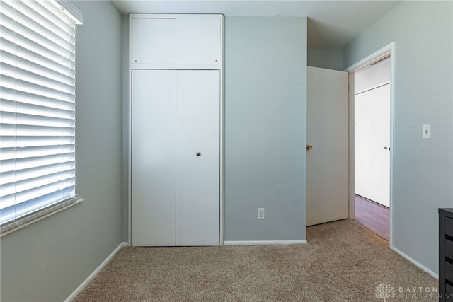 unfurnished bedroom with light carpet, multiple windows, and a closet