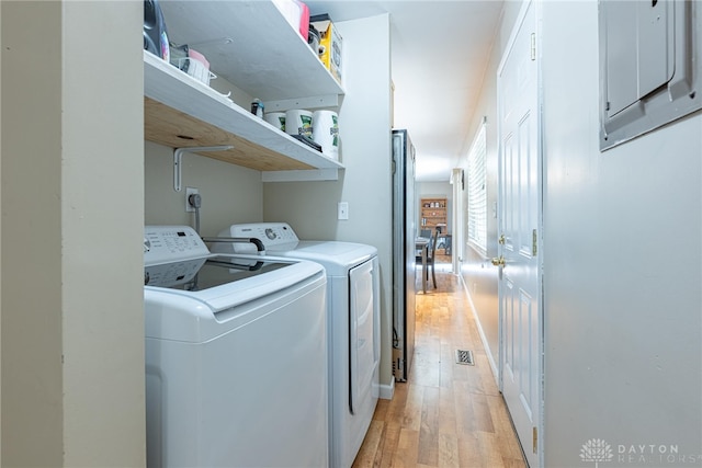 clothes washing area featuring washing machine and clothes dryer and light hardwood / wood-style flooring