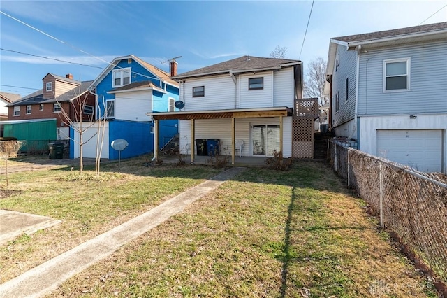 rear view of property featuring a garage and a lawn