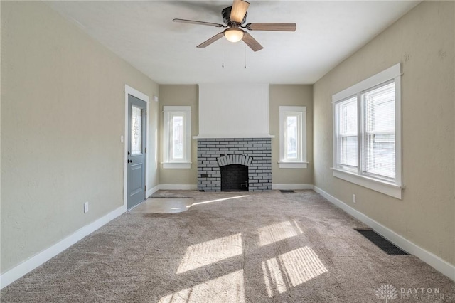 unfurnished living room with ceiling fan, carpet, and a brick fireplace