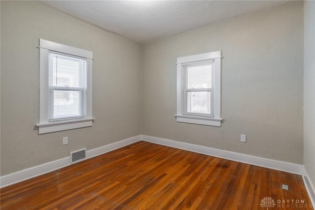 empty room featuring a healthy amount of sunlight and wood-type flooring