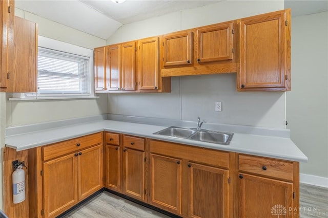 kitchen featuring lofted ceiling, sink, and light wood-type flooring