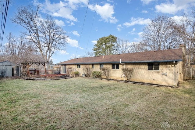 rear view of property featuring a pergola and a lawn