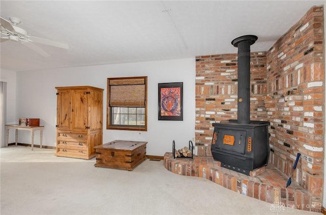 living room featuring carpet floors, a wood stove, and ceiling fan