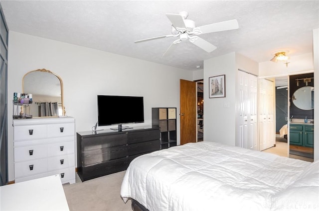 carpeted bedroom featuring ceiling fan, ensuite bathroom, and a textured ceiling