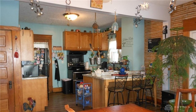 kitchen with dark hardwood / wood-style flooring, kitchen peninsula, and a breakfast bar area