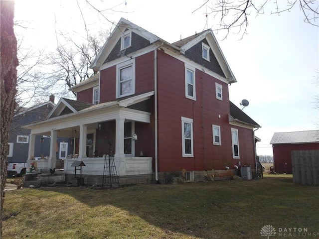 view of home's exterior featuring cooling unit, covered porch, and a lawn