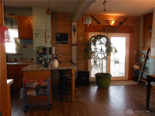 interior space featuring pendant lighting, sink, dark hardwood / wood-style floors, light stone countertops, and a kitchen bar