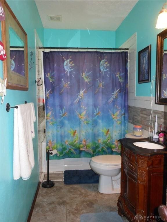 full bathroom featuring shower / tub combo, tile walls, vanity, tile patterned floors, and toilet