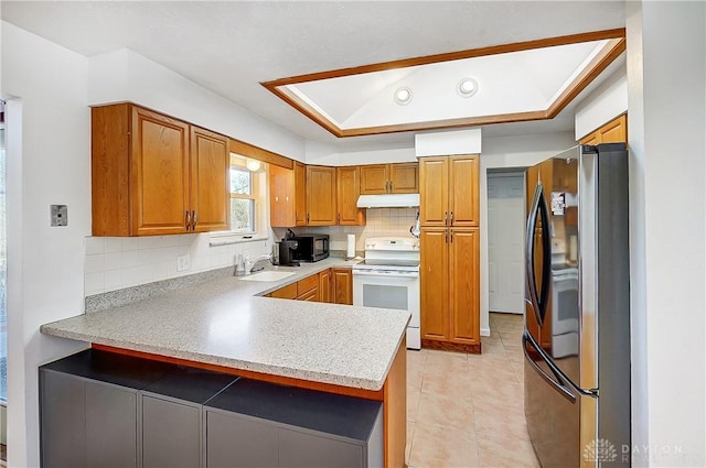 kitchen featuring white range with electric cooktop, under cabinet range hood, light countertops, freestanding refrigerator, and brown cabinetry