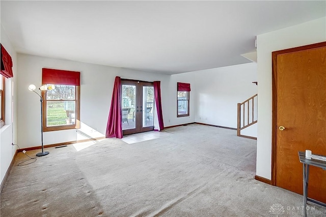 unfurnished room with light carpet, baseboards, stairway, and french doors